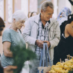 Senior tourist couple shopping for lemons at street market in city