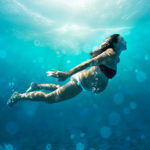 Underwater view of pregnant woman swimming